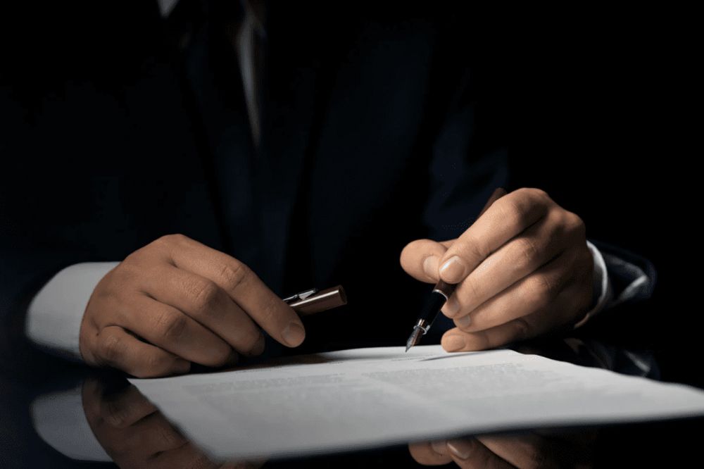 Person signing a document with a pen in a business setting, highlighting professionalism and attention to detail.